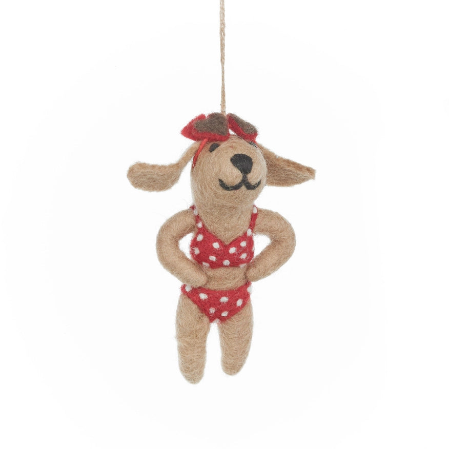 A handmade felt dog is shown, wearing a red and white polka dot bikini with a matching bow in its hair and sunglasses on its head.