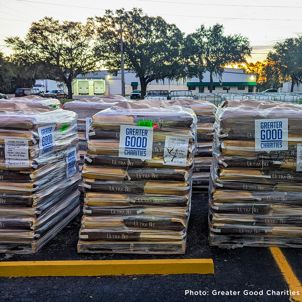 Pallets of bee feed labeled “Greater Good Charities” are stacked for disaster relief, ready for distribution. Photo by Greater Good Charities.