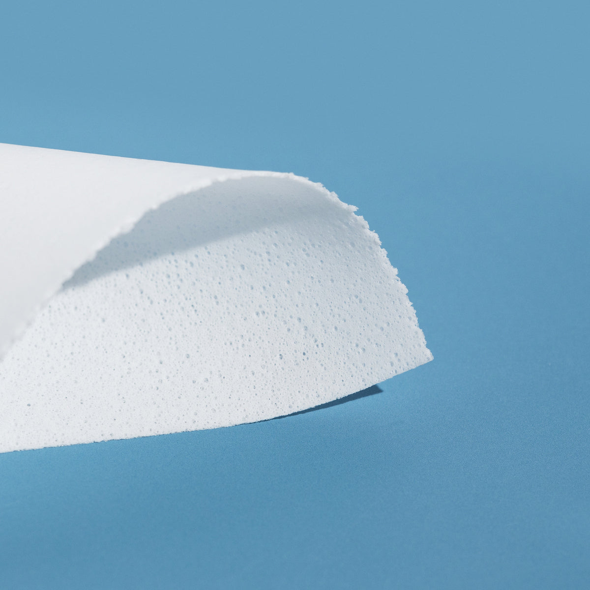 Close-up of a single OceanEco Laundry Detergent Strip folded, displayed on a soft blue background, highlighting its compact, ultra-concentrated design.