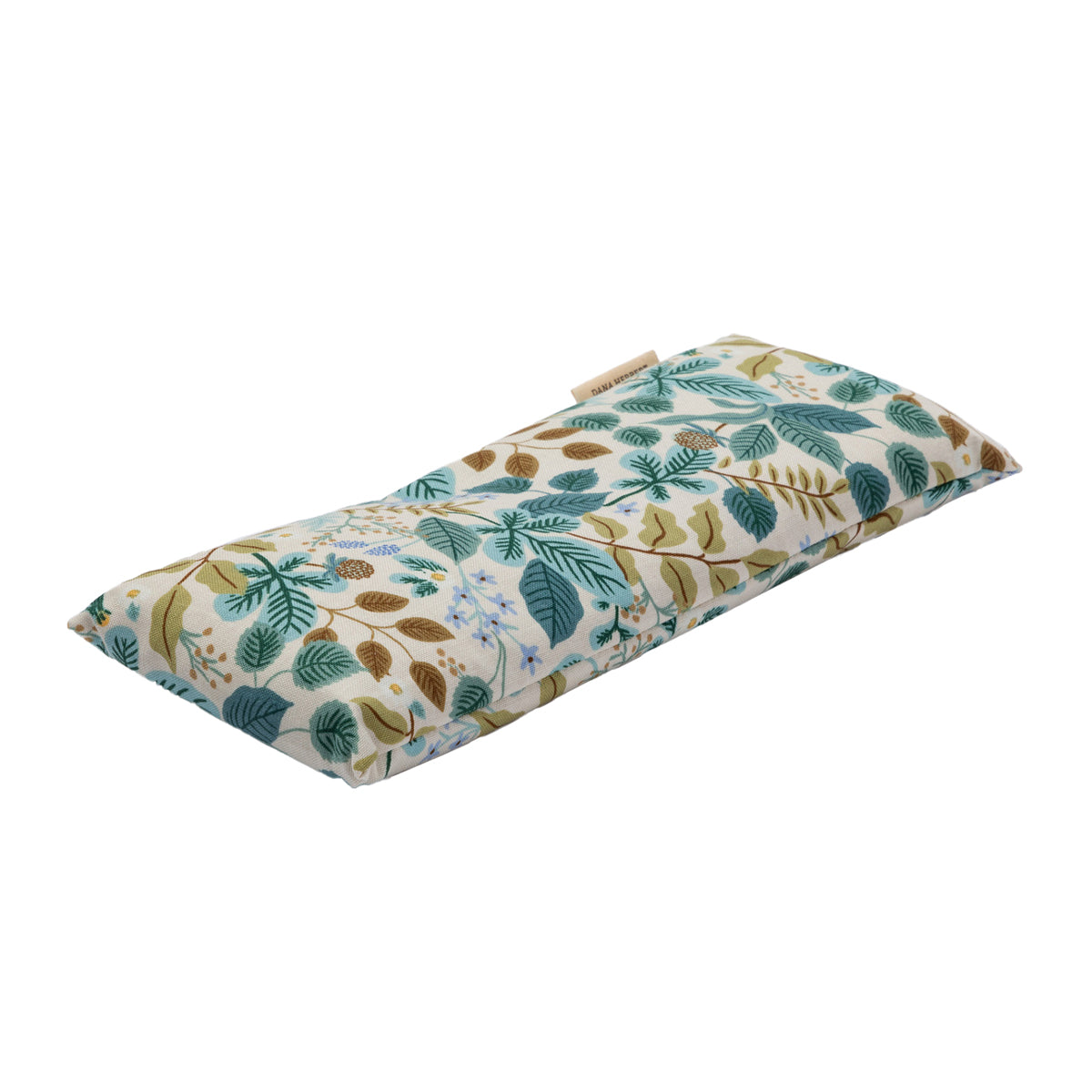 An eye pillow by Dana Herbert has a botanical pattern with teal and brown leaves and light blue flower clusters. It is shown at an angle.