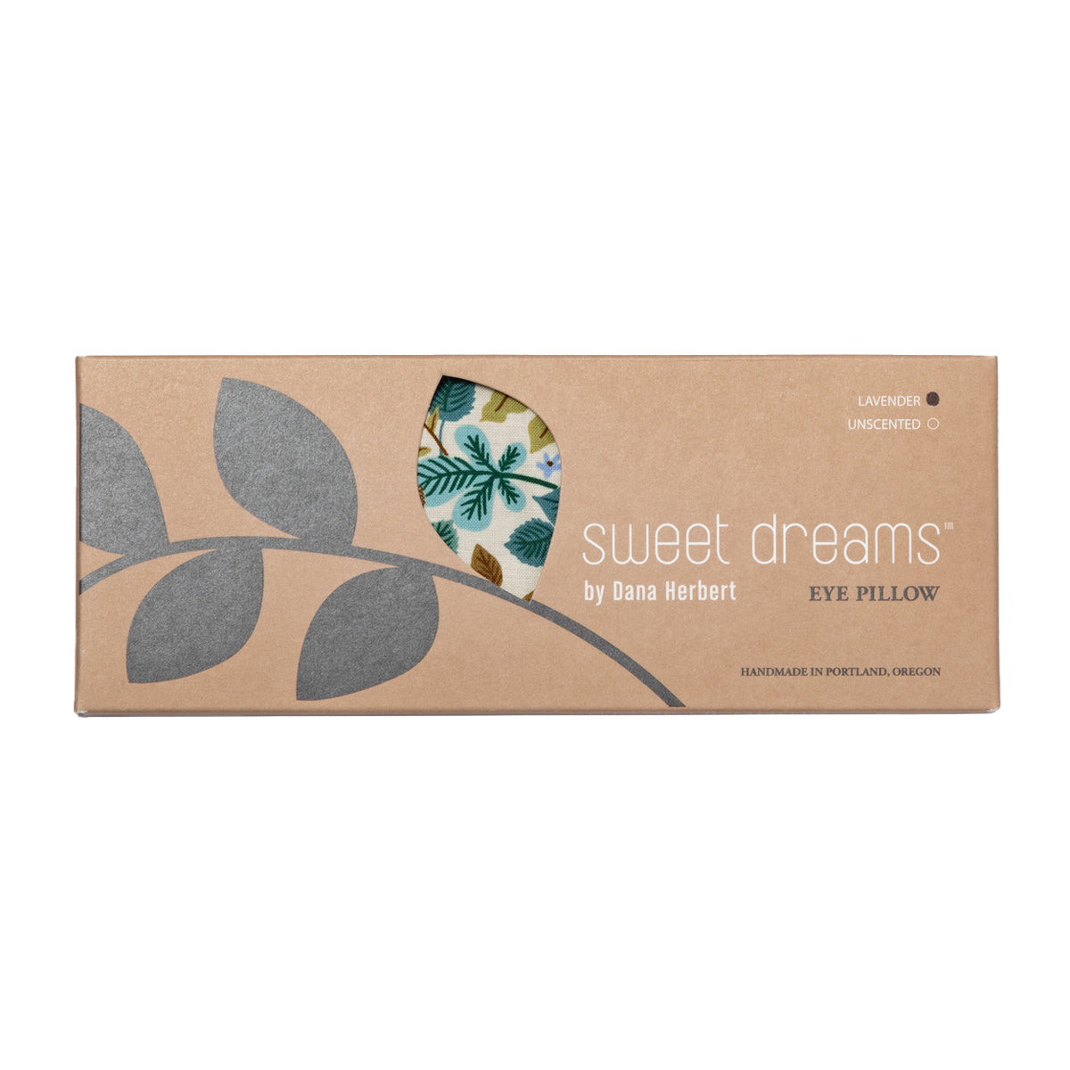 A cardboard box for a "sweet dreams" eye pillow by Dana Herbert is on a white background. A cutout shows a glimpse of a botanical patterned pillow inside. The box says it is lavender and unscented.