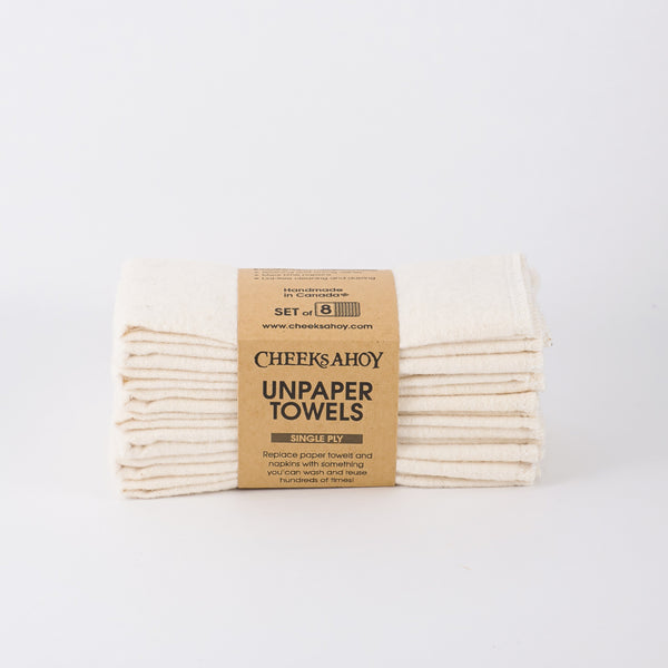 A stack of eight Cheeks Ahoy Unpaper Towels is shown, consisting of a neutral off-white or beige color. The cloths are held together by a paper band that identifies them as a set of eight single-ply towels.
