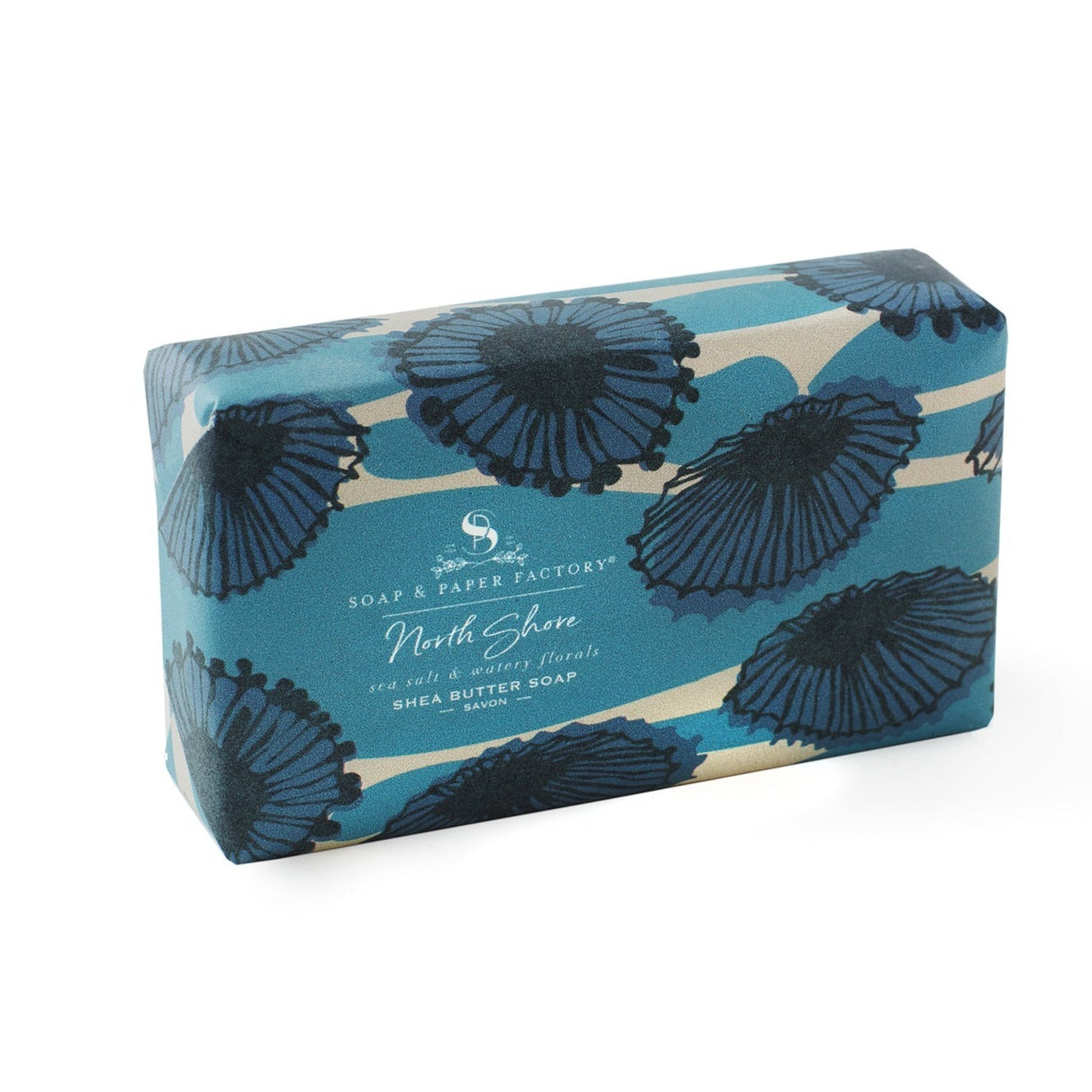 A blue and cream striped 'Soap & Paper Factory' shea butter soap bar with a pattern of dark blue floral shapes. The wrapper is for the "North Shore" scent, which is described as "sea salt & watery florals."