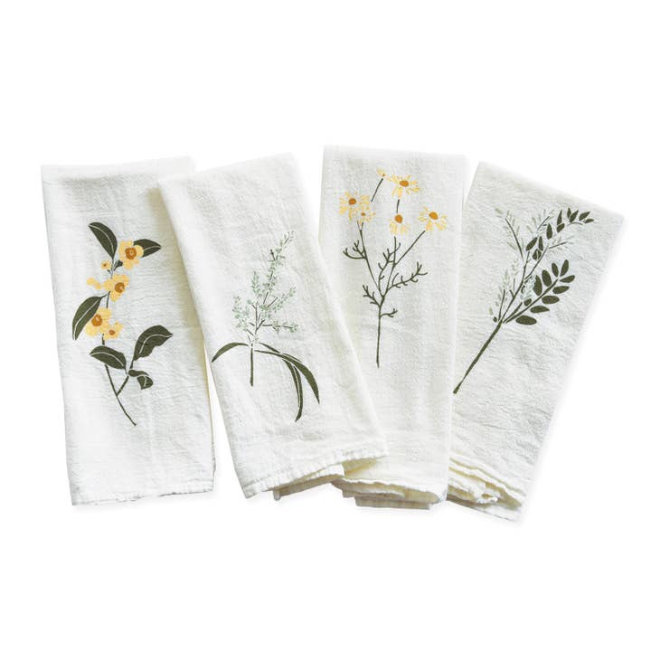 A lovely set of four white napkins is shown folded, each with a different botanical design of branches and flowers in shades of yellow and green.