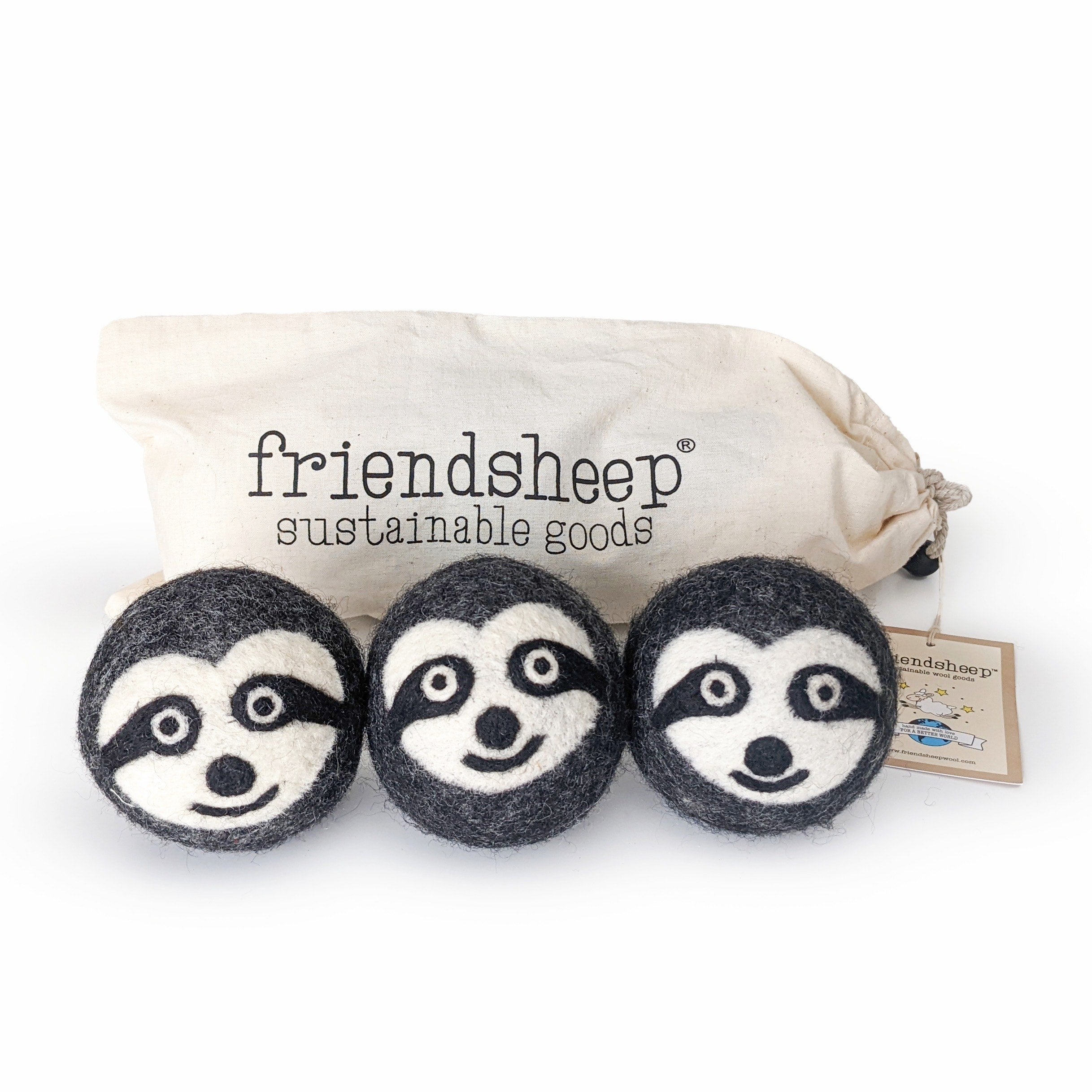 A set of three Friendsheep sustainable goods wool dryer balls are shown decorated with a cute sloth face. They are sitting in front of their white canvas drawstring bag.