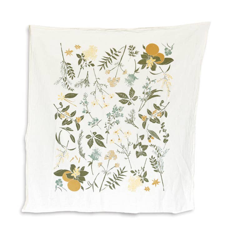 A white kitchen towel is decorated with a whimsical botanical pattern of flowers and leaves in a mix of soft yellow, dusty blue-green, and olive green.
