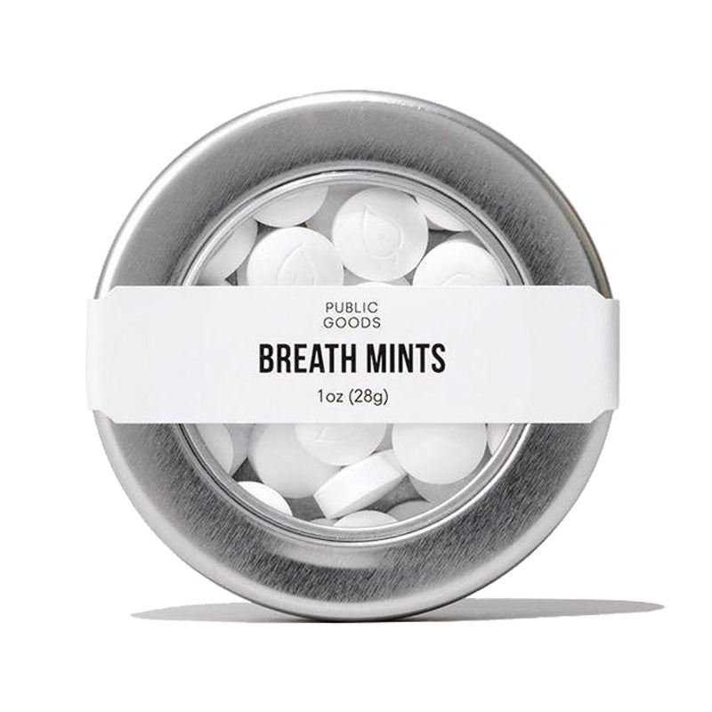 A round tin of 'Public Goods' breath mints has a clear lid showing the white mints inside. "BREATH MINTS" is written in bold on the label.