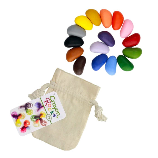 Sixteen colorful, rock-shaped Crayon Rocks are fanned out above a natural drawstring bag, showcasing the unique form designed to aid grip.