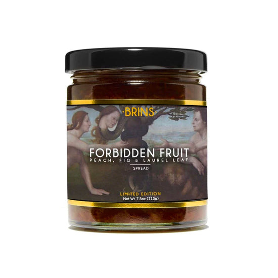 A jar of amber-colored Brins Forbidden Fruit spread is shown on a white background. The label has an artistic design featuring human figures and a serpent in a tree. The label identifies the spread as containing peach, fig and laurel leaf.