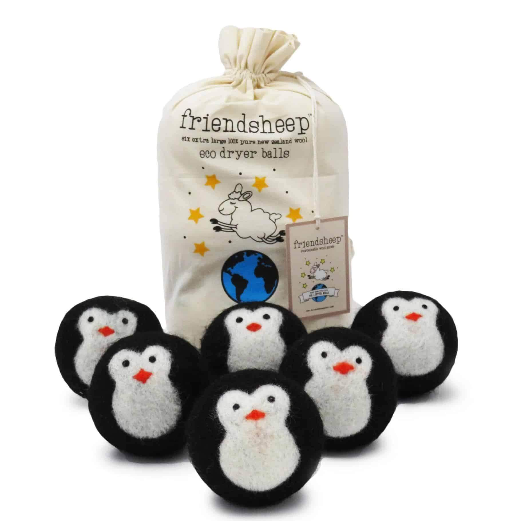 Six wool dryer balls designed with black and white penguin patterns, arranged neatly next to their natural cotton drawstring bag on a clean white background.