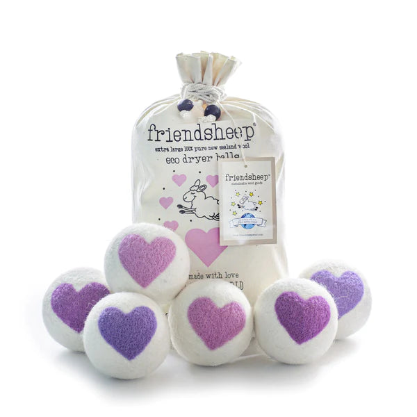 Six wool dryer balls featuring 'Lovely Day' purple heart designs, displayed next to a natural cotton drawstring bag on a plain surface. Crafted from 100% organic New Zealand wool, sustainable and long-lasting laundry accessory.