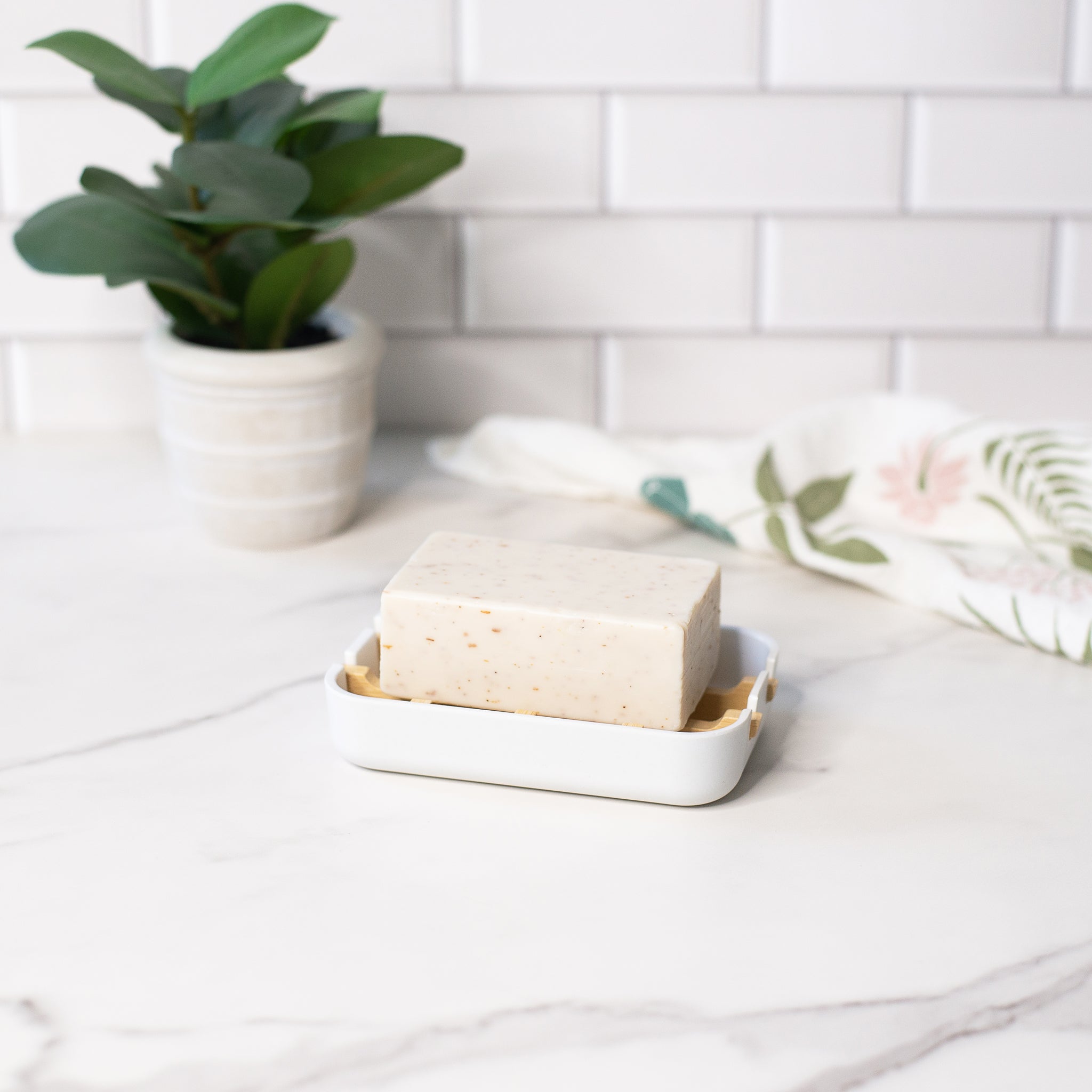 A sustainable soap dish with a slatted bamboo tray holds a bar of natural soap, ready for a fresh cleansing.