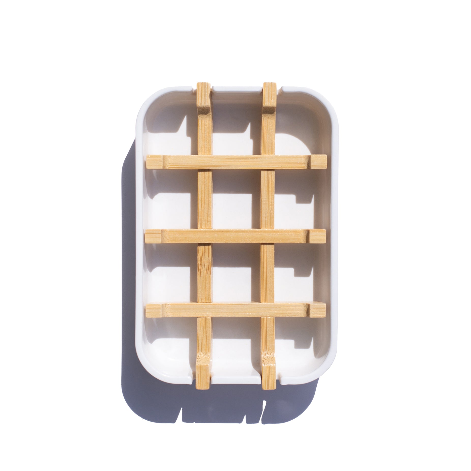 A white soap dish with a slotted insert made of natural bamboo. It is designed to let water drain from the soap.