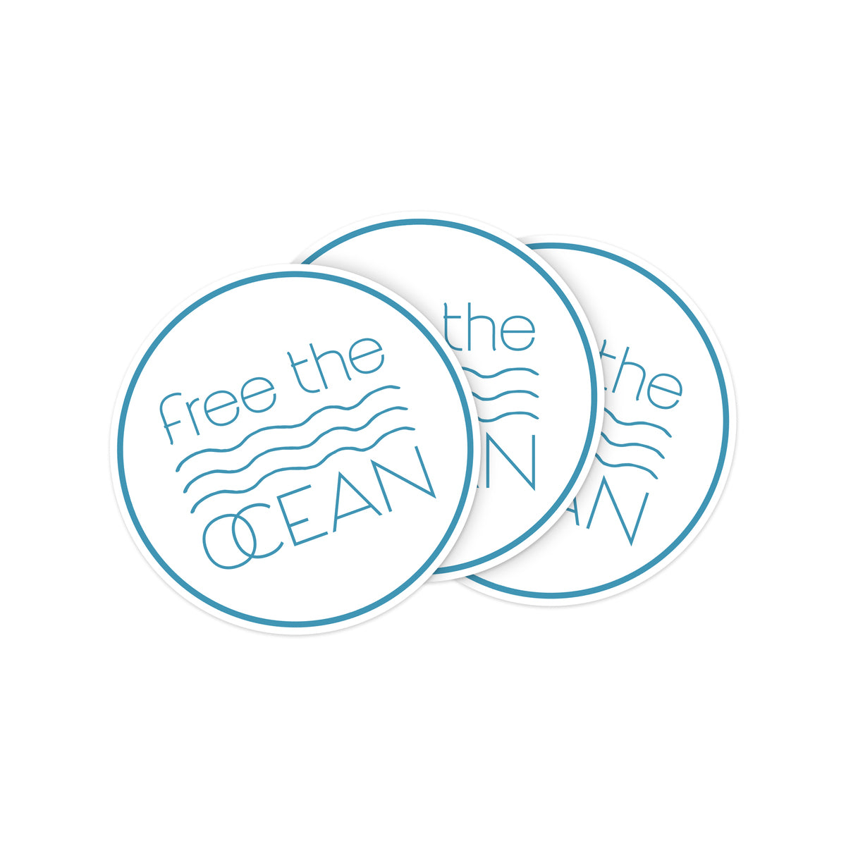 A set of three circular stickers with a white background and blue text that reads "free the OCEAN" with wavy lines in the middle. The stickers are shown slightly overlapping.