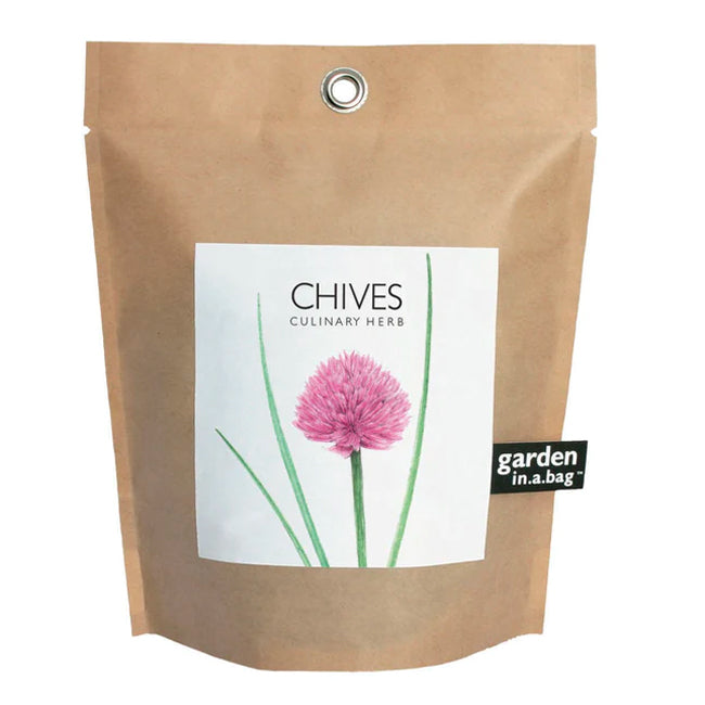 A brown paper "garden in a bag" pouch is shown with a white label featuring a vivid illustration of a chive plant. The label identifies the contents as "CHIVES" a "CULINARY HERB" and hints at the delightful flavor to come.