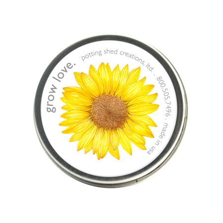 A circular garden sprinkles tin with a beautiful yellow sunflower illustration on the lid. The text "grow love" is visible on top.