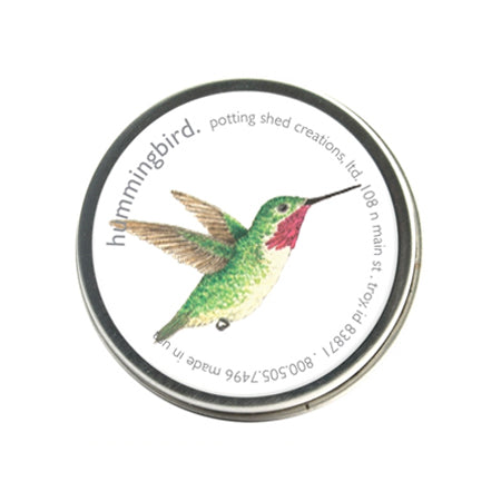 A silver tin ofgarden sprinkles with a white label on the lid. The label features a watercolor illustration of a green hummingbird in flight, with the text 'hummingbird, potting shed creations' around the edge.
