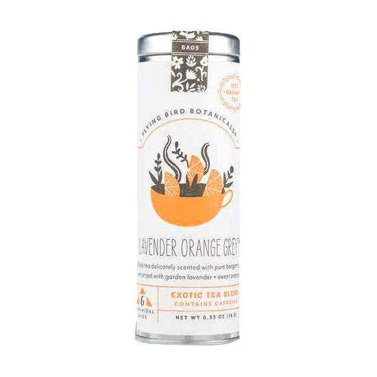 A metal tin of "Flying Bird Botanicals" "Lavender Orange Grey" tea is shown, featuring a label with an illustration of a steaming teacup full of orange slices. The label describes the blend as containing "pure bergamot" "garden lavender" and "sweet orange" and notes that it "CONTAINS CAFFEINE".