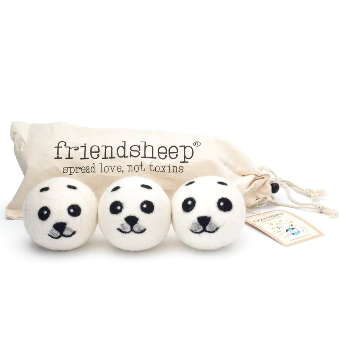 A set of three Friendsheep sustainable goods wool dryer balls are shown, each decorated with a cute seal face. They are sitting in front of their white canvas drawstring bag.