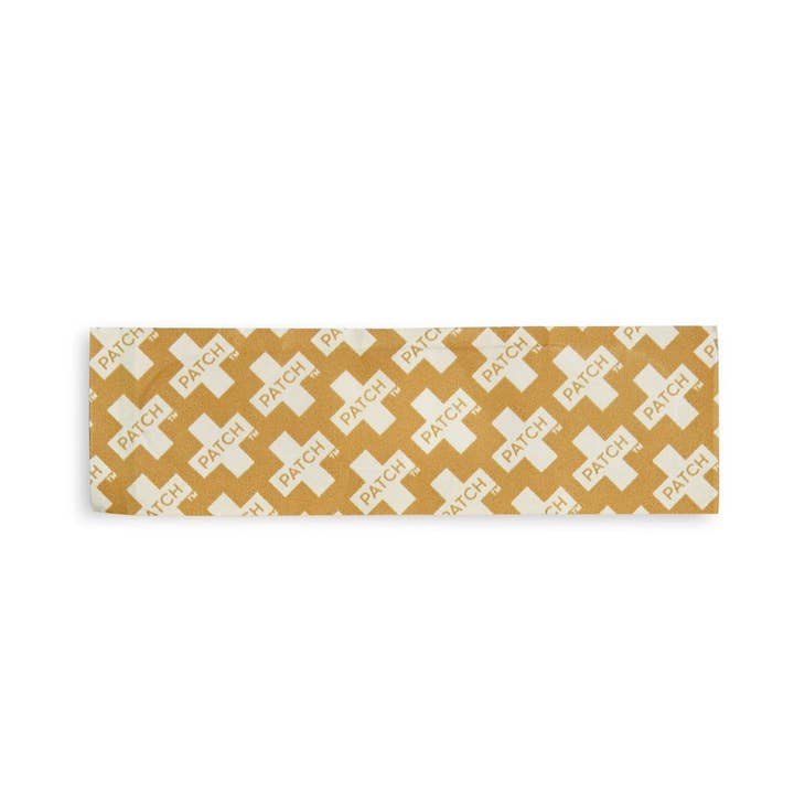 Close-up of a single beige bamboo-fiber bandage strip laid flat on a white background, displaying its woven texture and gauze center.