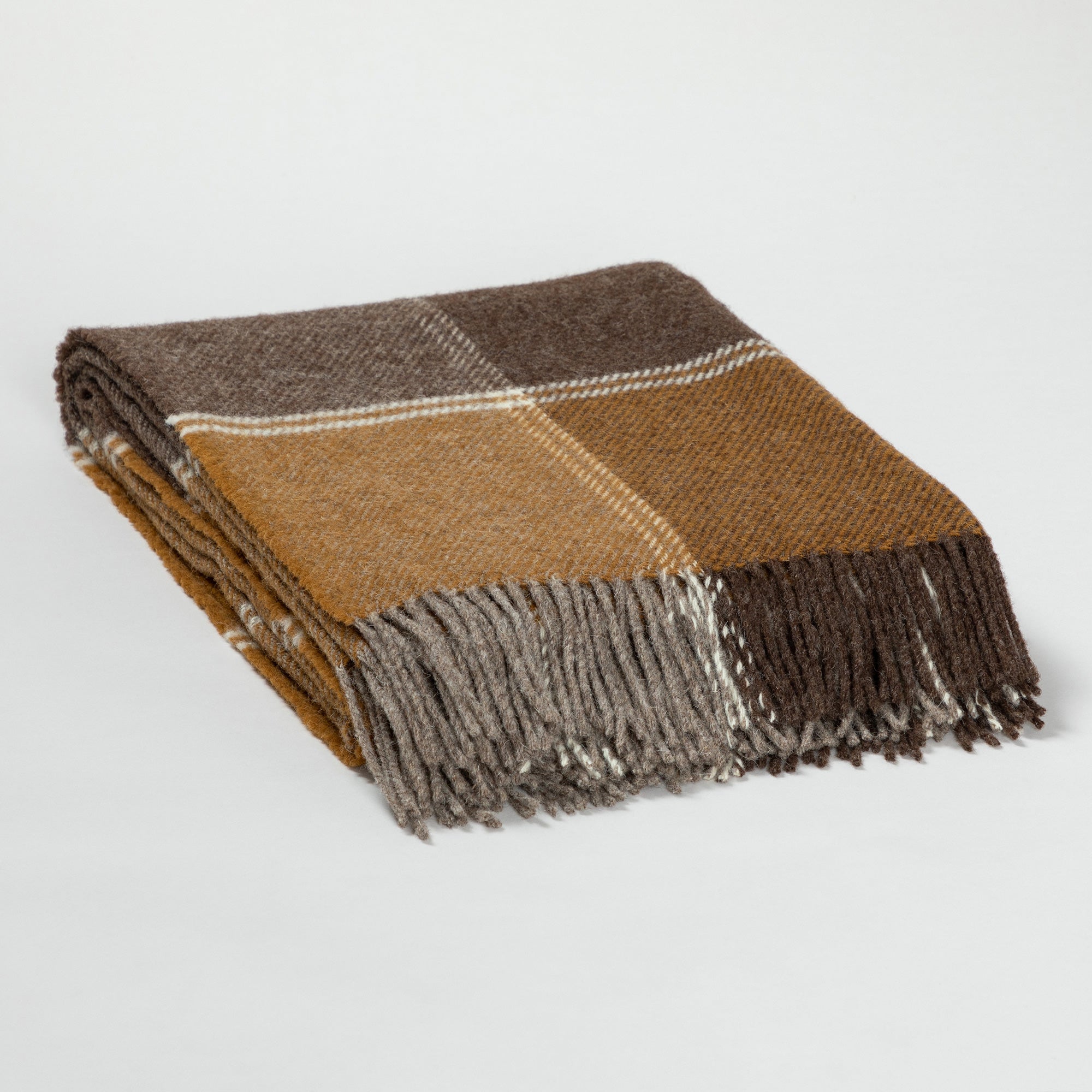 Folded wool throw blanket with plaid patterns in mustard yellow, brown, and beige tones, featuring fringed edges on a white surface.