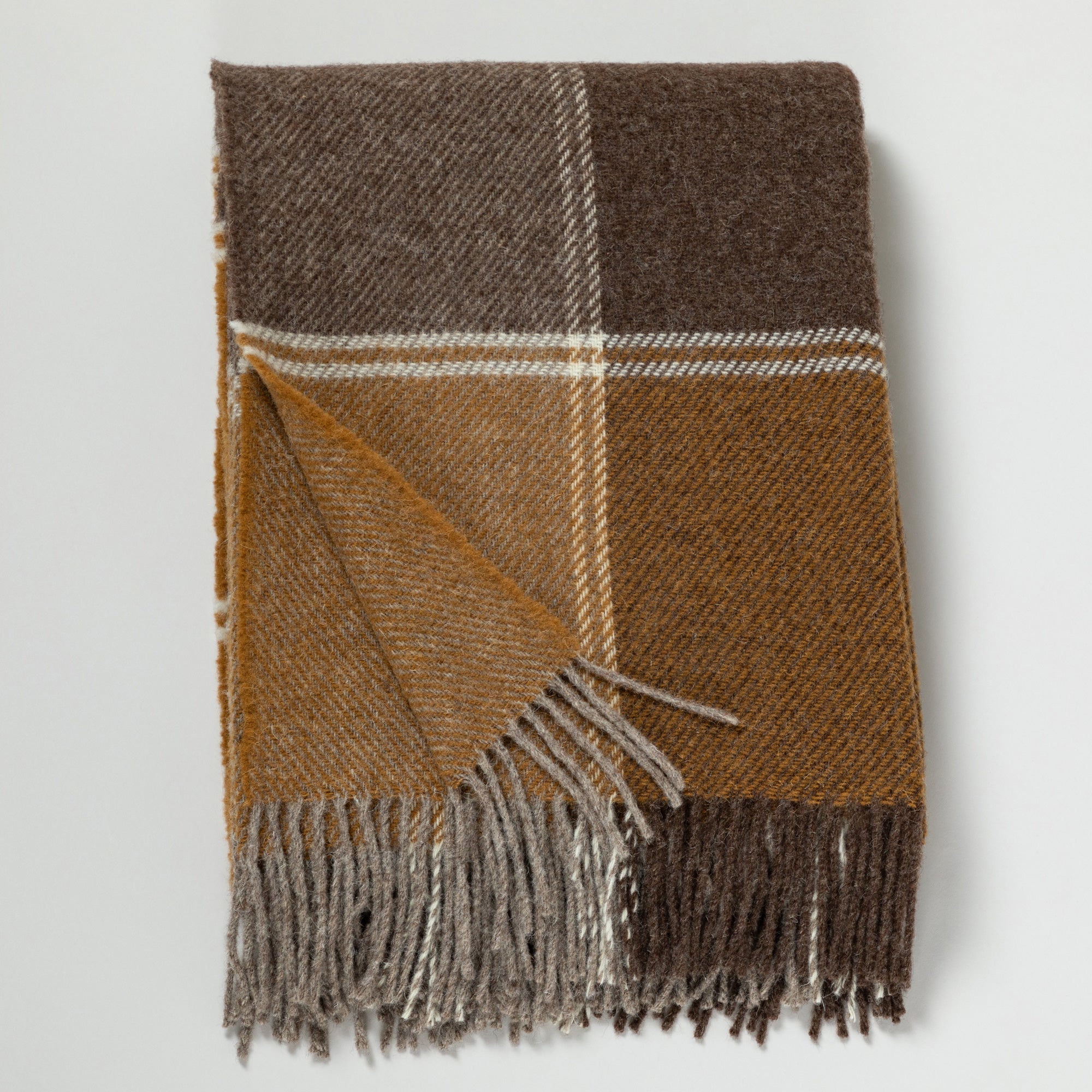 Folded wool throw blanket with plaid patterns in mustard yellow, brown, and beige, featuring fringed edges on a white background.