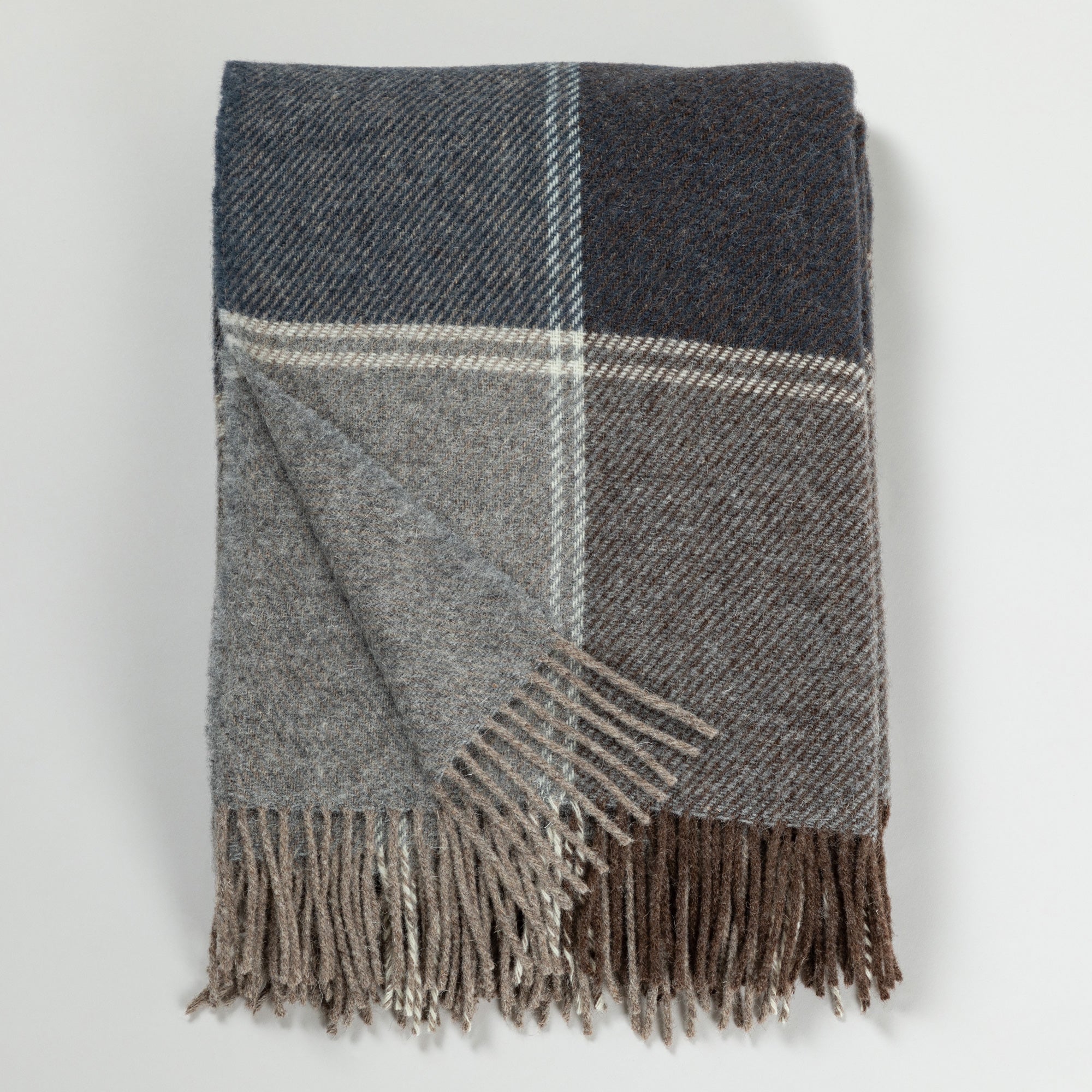 Folded 100% wool throw blanket with a gray and brown plaid pattern and long fringe, handmade by artisans in Ukraine for cozy winter warmth.