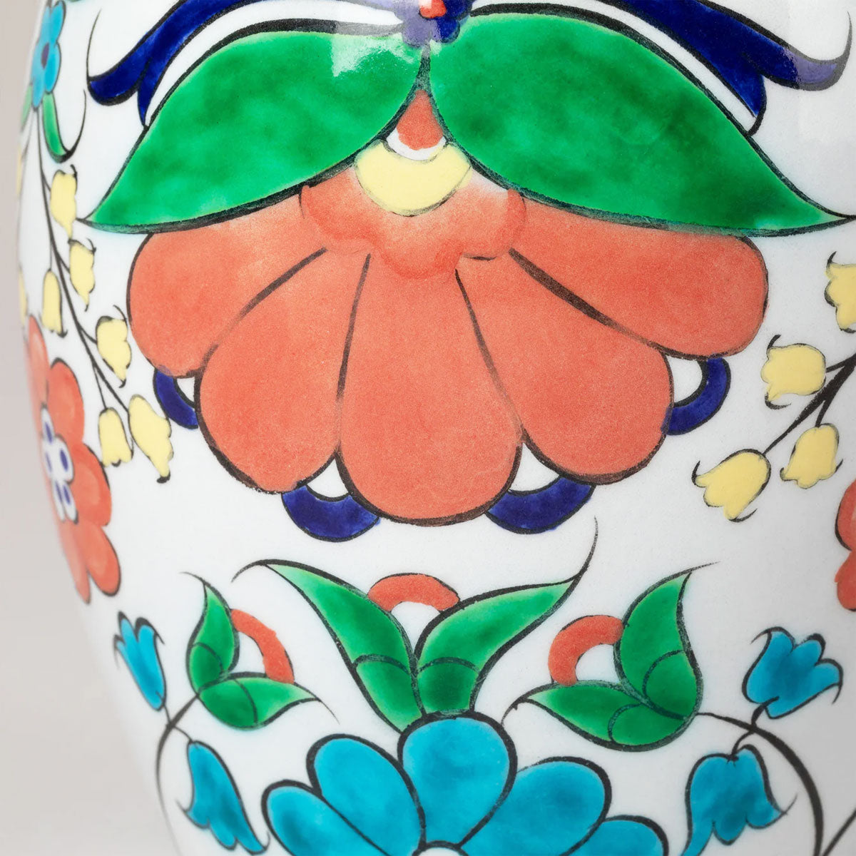 Close-up of a ceramic vase with colorful floral patterns on a white background