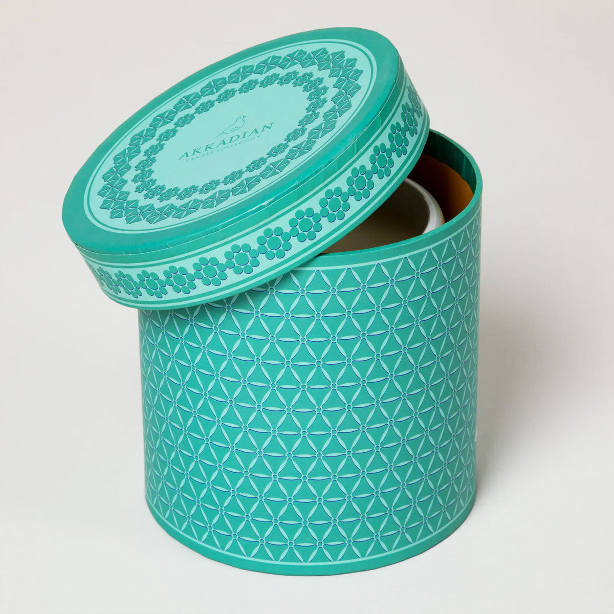 Teal patterned cylindrical container with lid on a white background