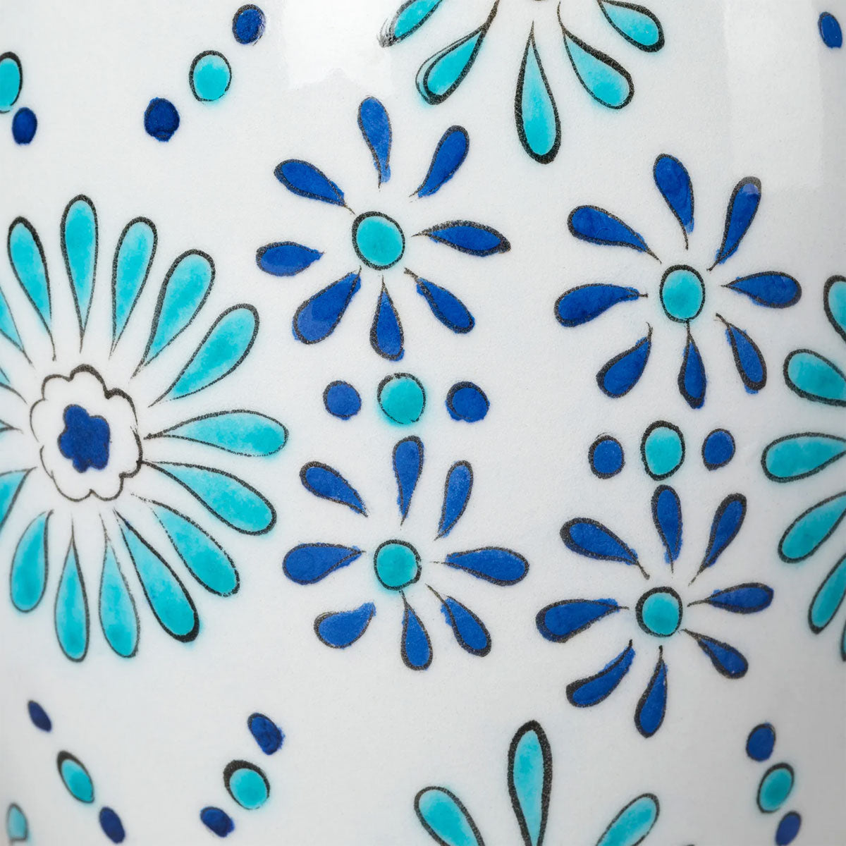 Close-up of a ceramic tile with blue and turquoise floral pattern on a white background