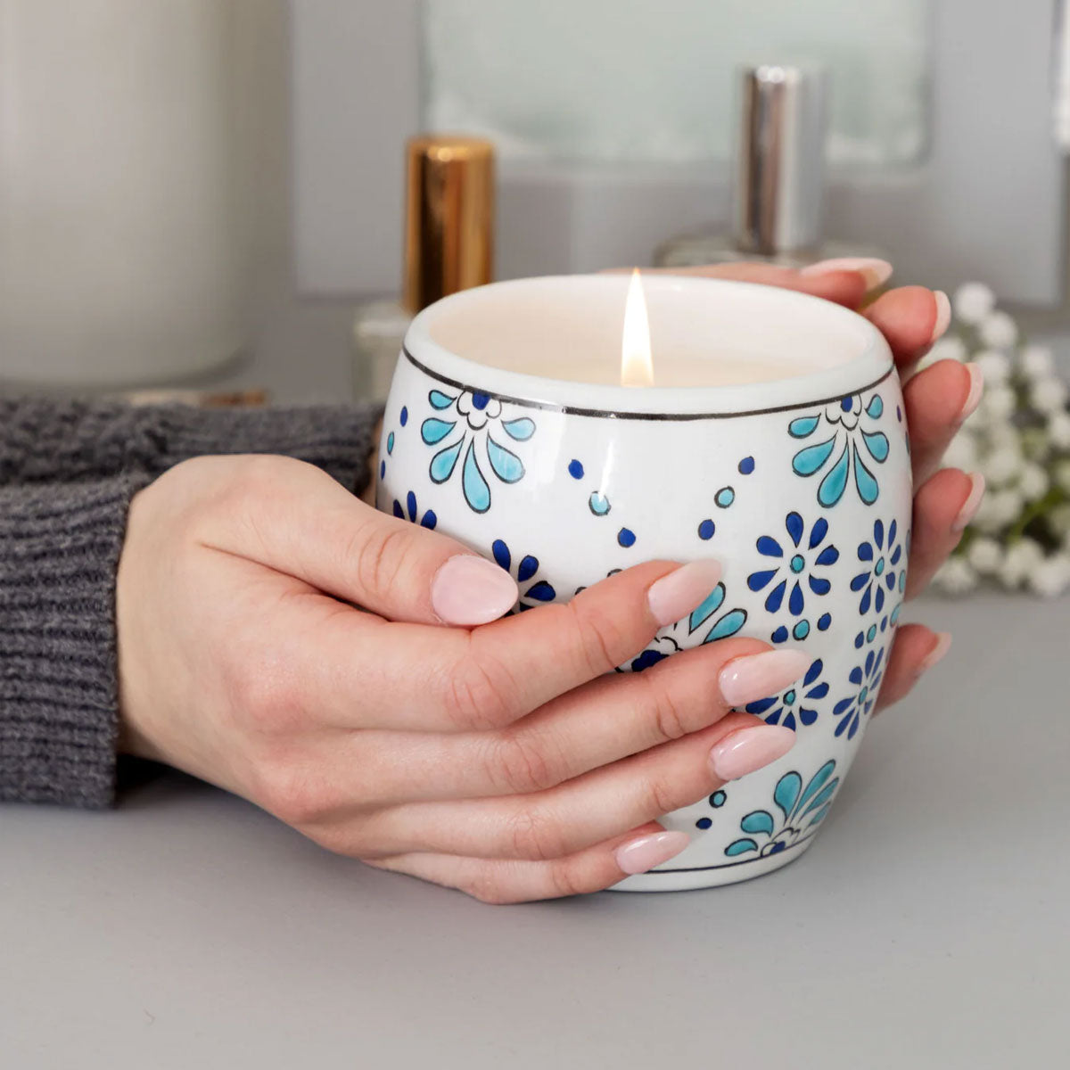 Person holding a floral-patterned candle in a kitchen setting