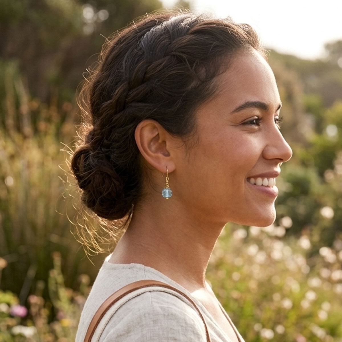 Woman with braided hair smiling outdoors in a natural setting
