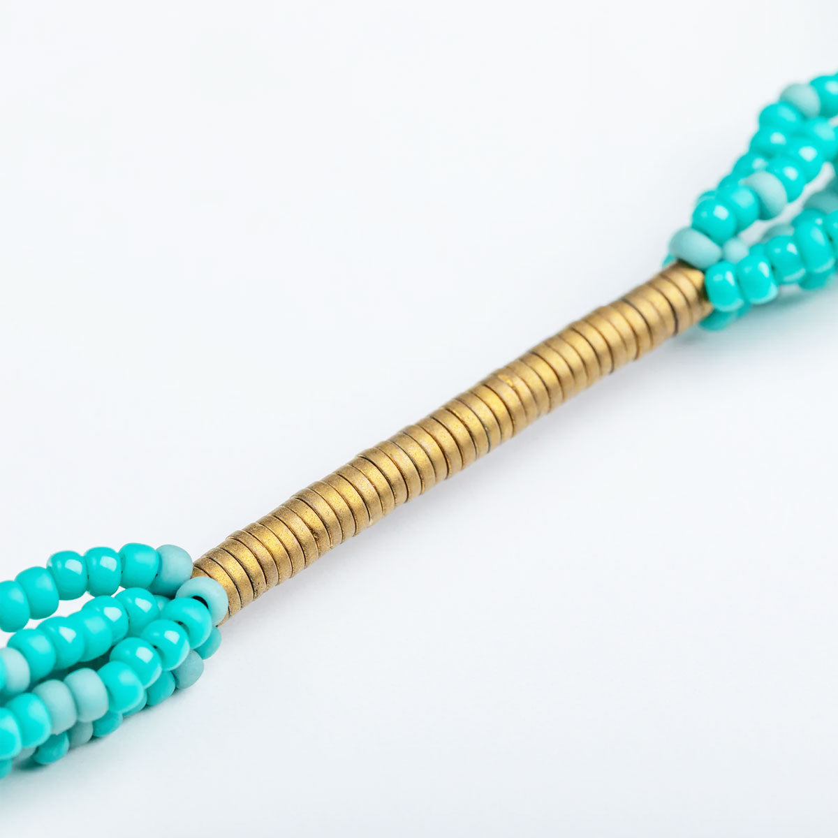 Beaded necklace stick with turquoise and gold beads on a white background