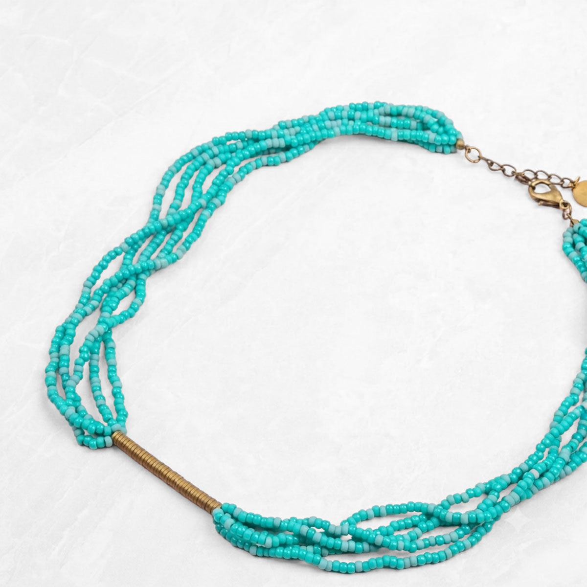 Turquoise beaded necklace with brass accents on a white background