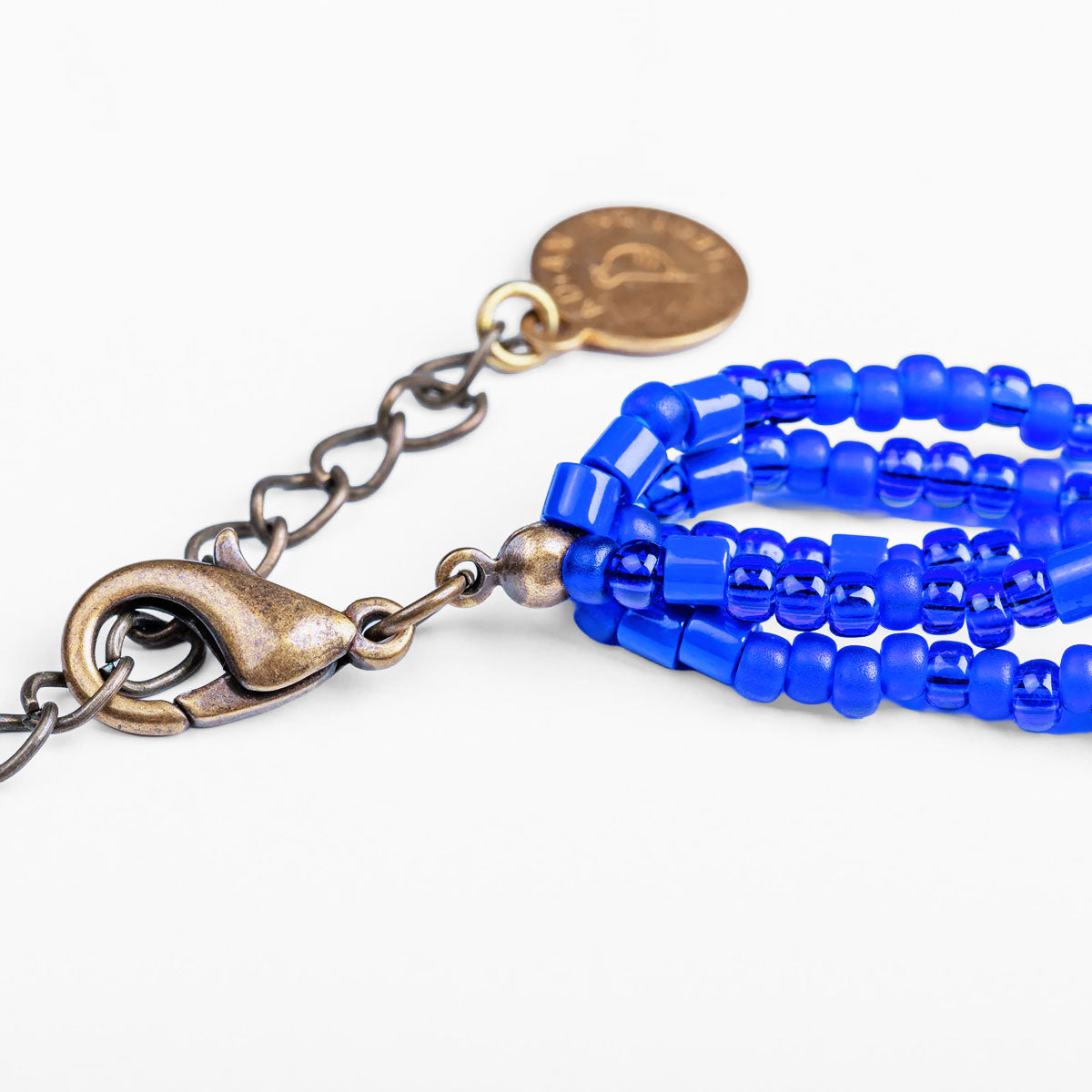 Blue beaded bracelet with bronze clasp on a white background