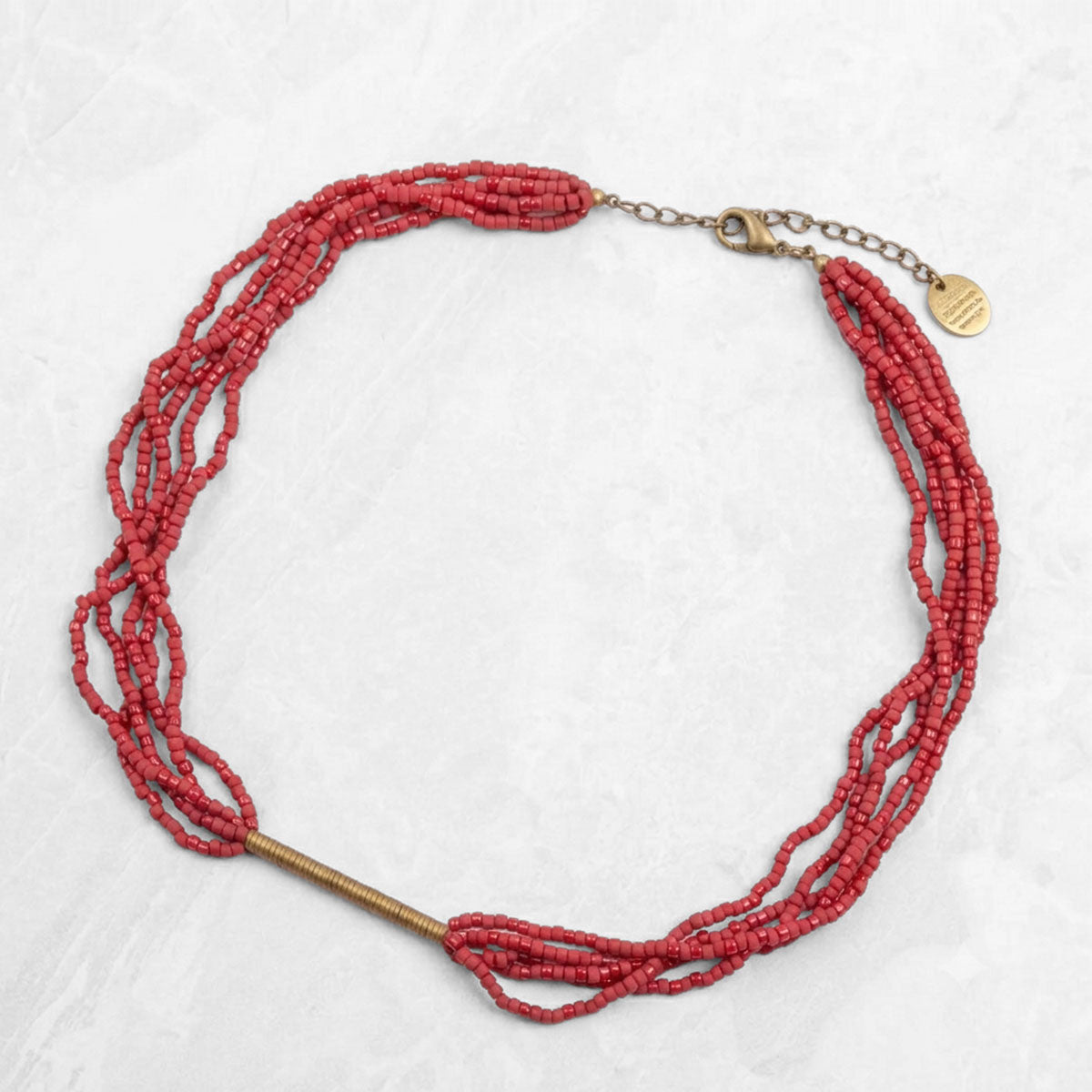 Red beaded necklace with brass clasp on a white background