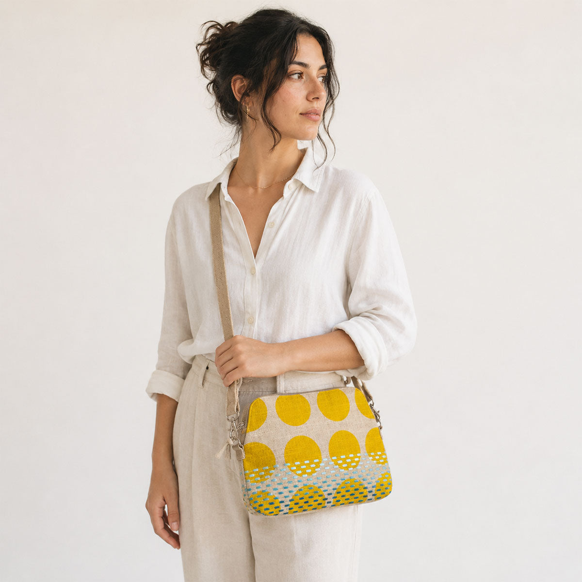 Woman holding a yellow and green patterned bag against a plain background