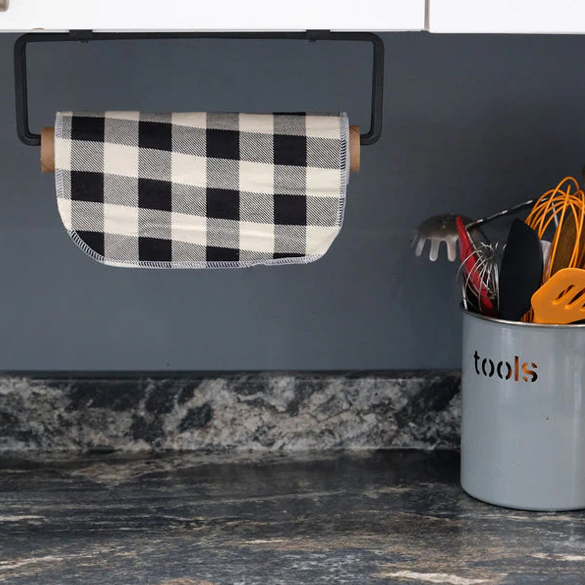 A single black and white buffalo check Cheeks Ahoy unpaper towel is shown on a paper towel holder under a kitchen cabinet.