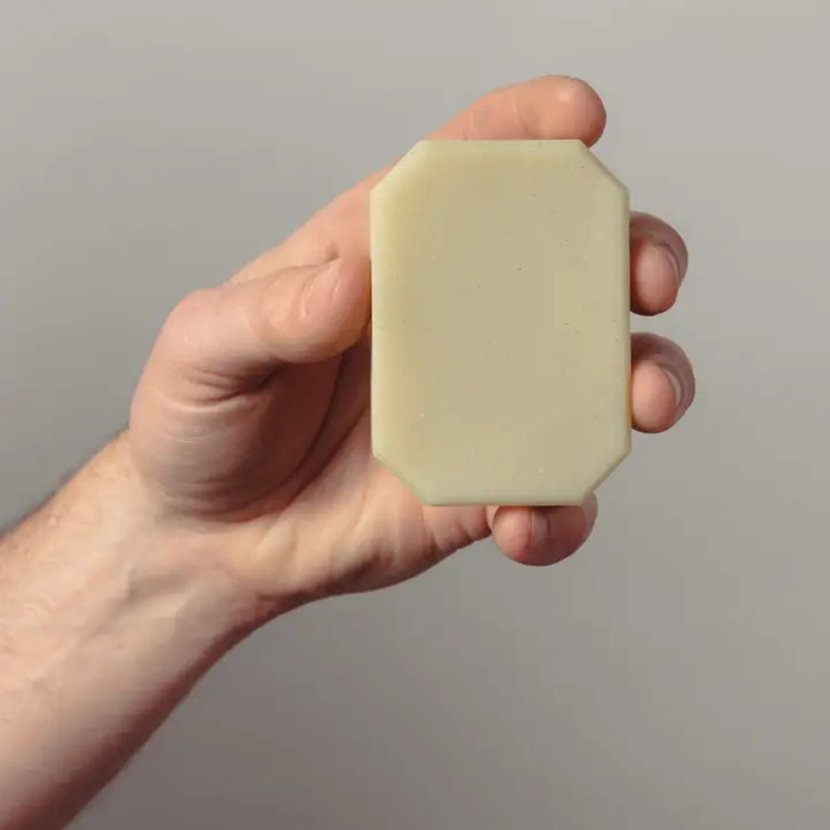 Hand holding a bar of Gardener soap against a plain background