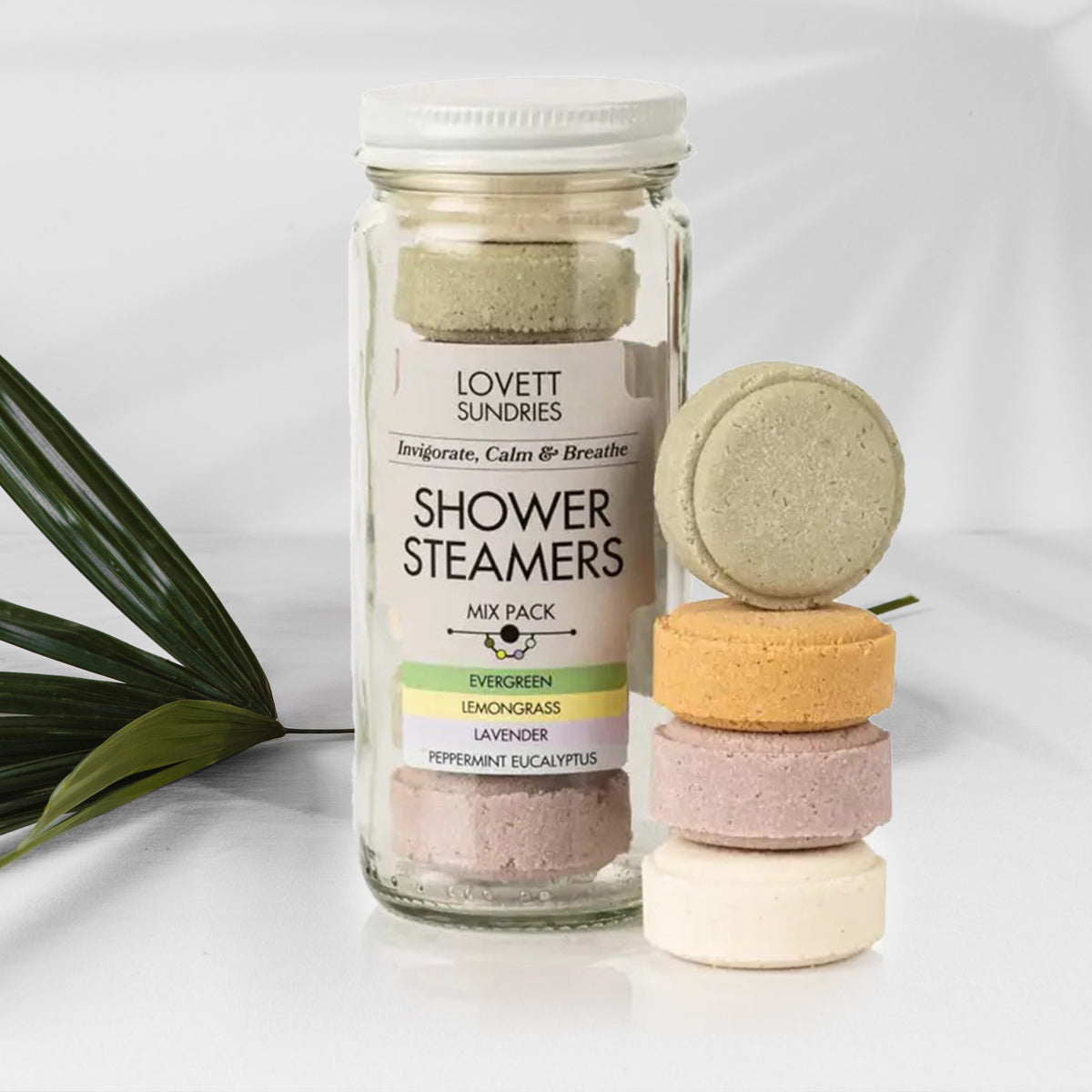 Glass jar of Lovett Sundries shower steamers with colorful bath bombs on a white background