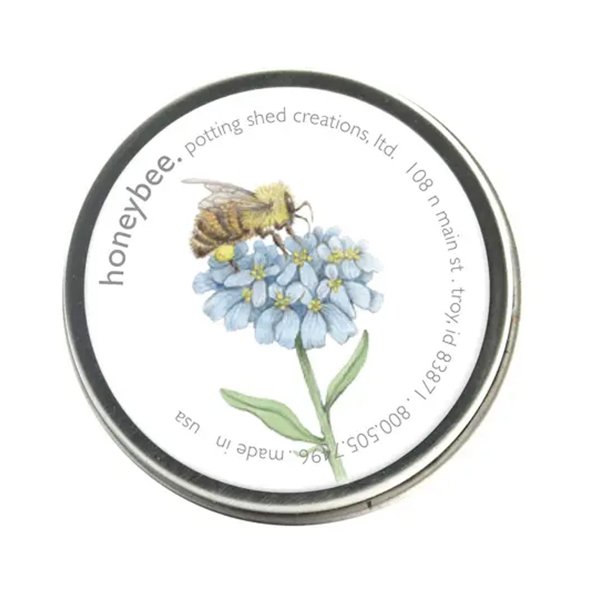 A silver tin of seeds with a white label on the lid. The label features a watercolor illustration of a honeybee on a cluster of light blue flowers, with the text 'honeybee. potting shed creations' around the edge.