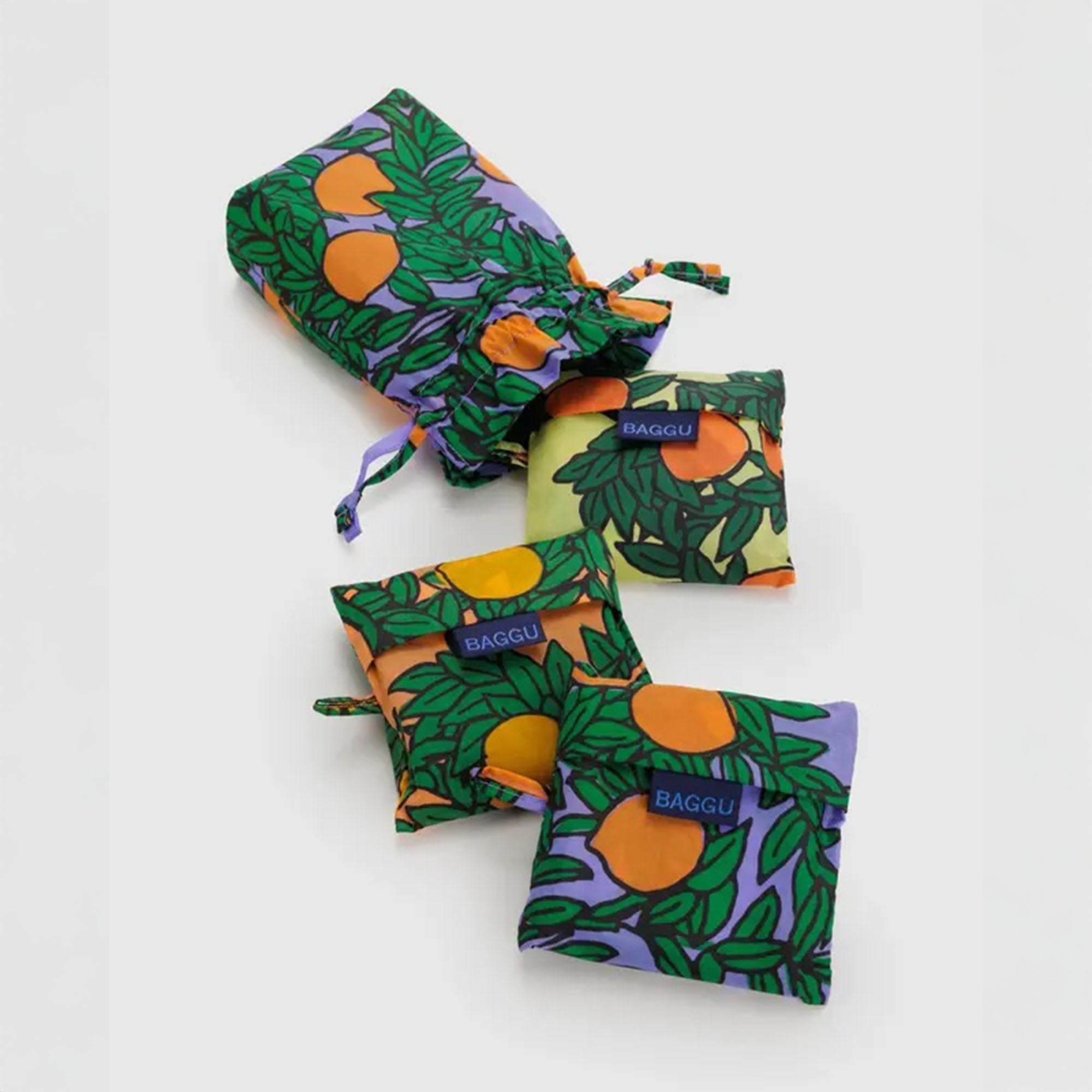A trio of BAGGU reusable bags from the Orange Trees collection, stacked to show the unique print and sturdy, spacious construction made from recycled ripstop nylon.