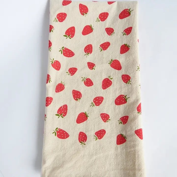 A hand-printed organic cotton tea towel, features a vibrant repeating pattern of red strawberries with green stems.