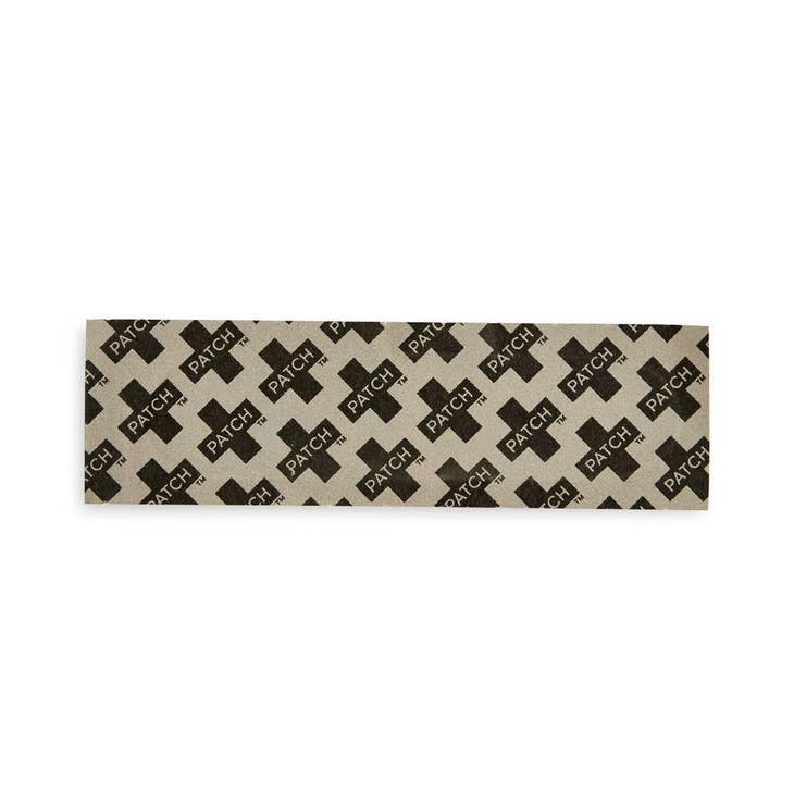 Close-up of a single activated charcoal bamboo-fiber bandage strip laid flat on a white background, displaying its woven texture and gauze center.