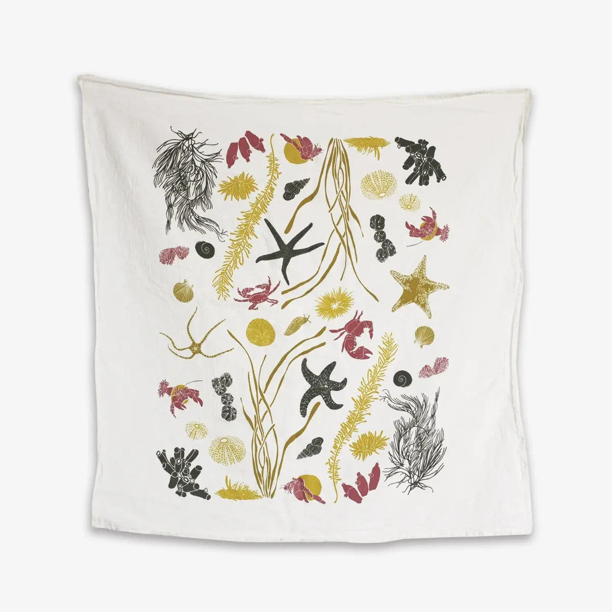 A white kitchen towel features a fun underwater pattern of starfish, crabs, sea urchins and seaweed in shades of black, coral pink and golden yellow.