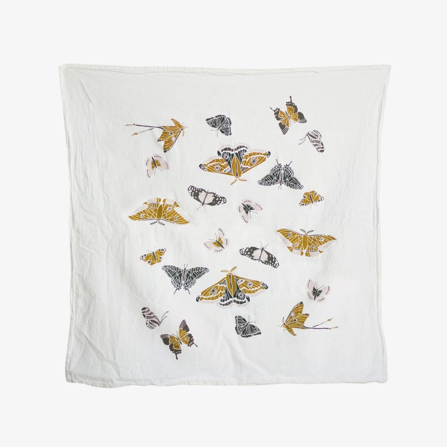 A white tea towel is decorated with a playful pattern of different moths in shades of gold, black and white.